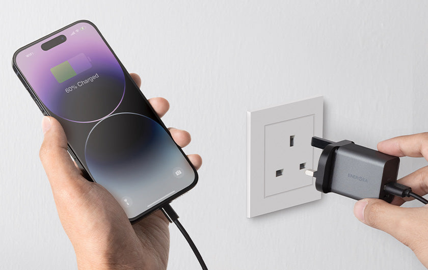 Image of a person charging their smartphone with an adapter plugged to a wall socket