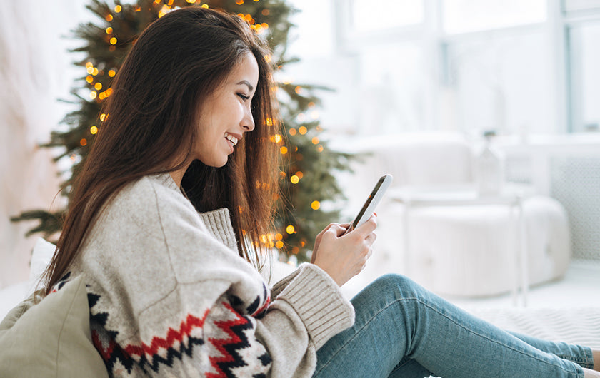 Image of a woman using her phone while sitting on a couch